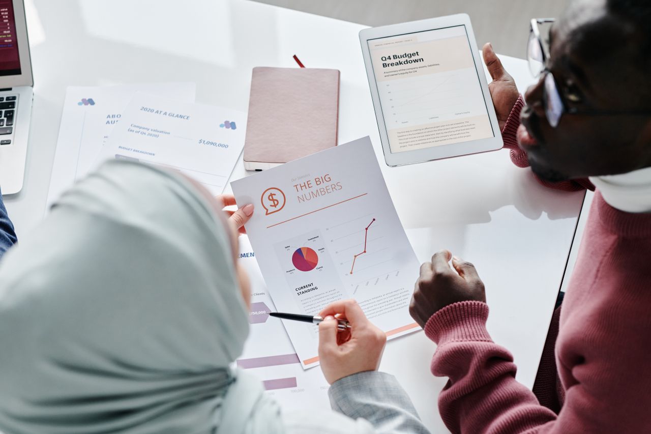 Two professionals examining financial reports, charts and a budget breakdown